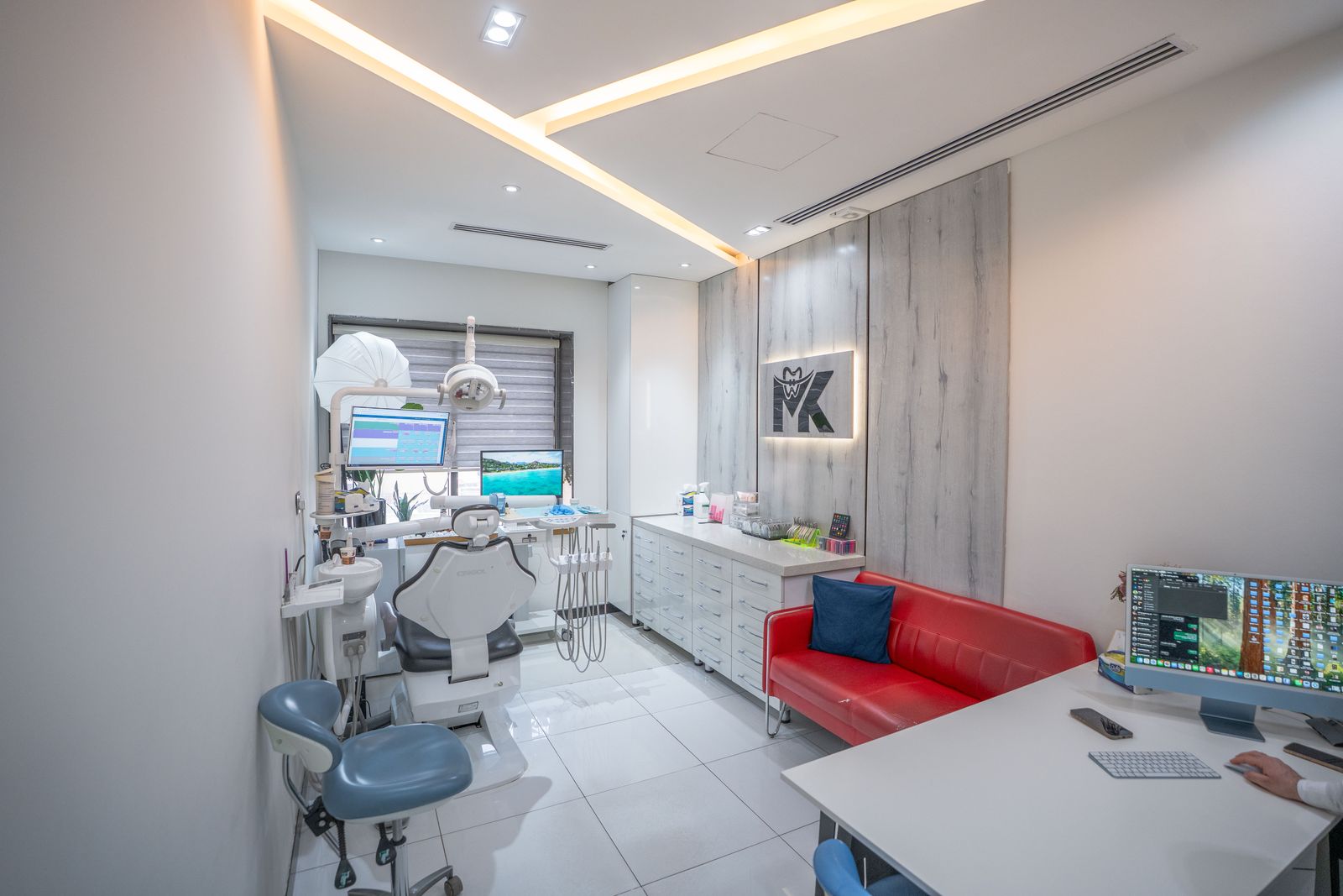 A treatment room with a red sofa and the MK logo on a wood-panelled wall