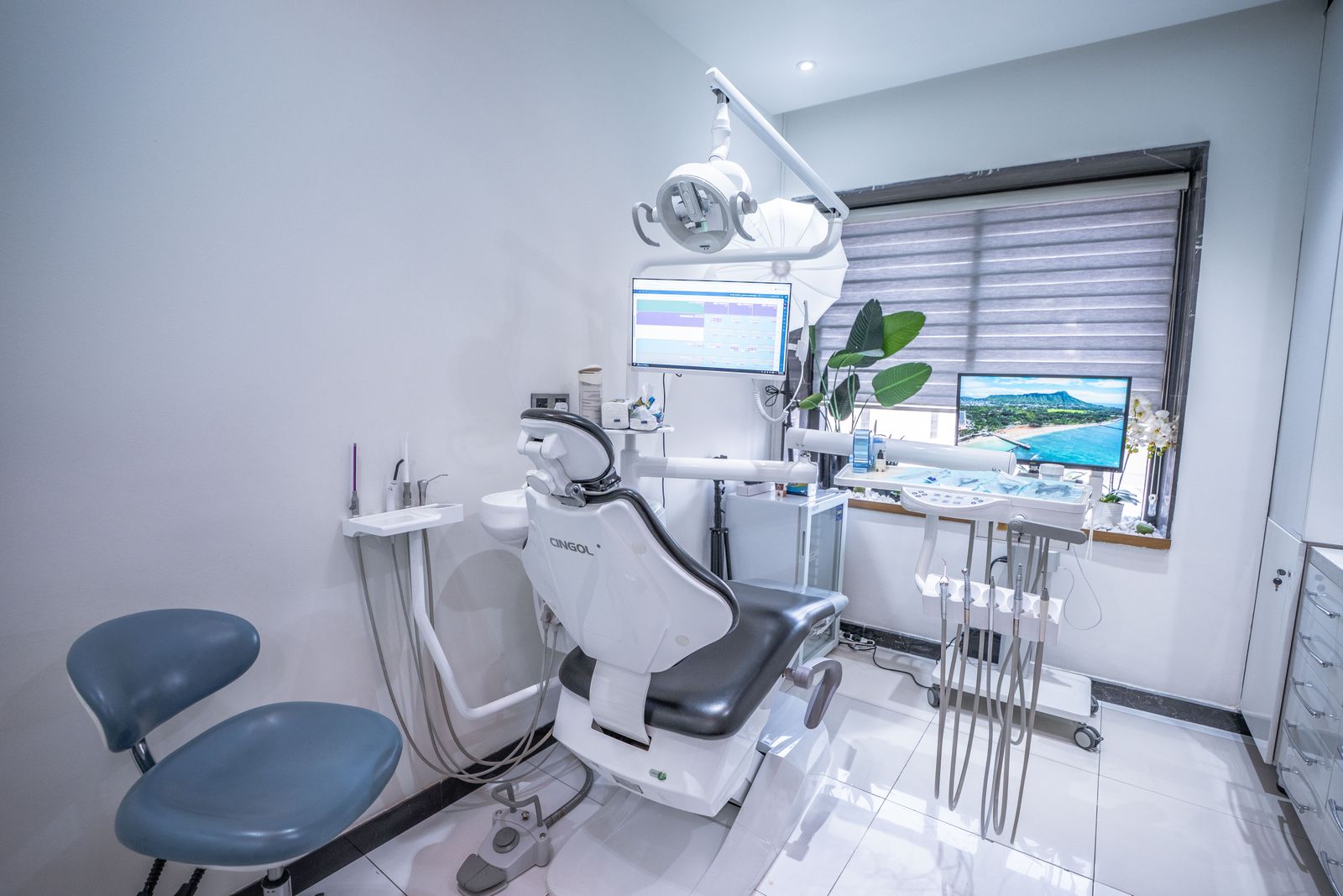 A treatment room with a grey dental chair beside the window