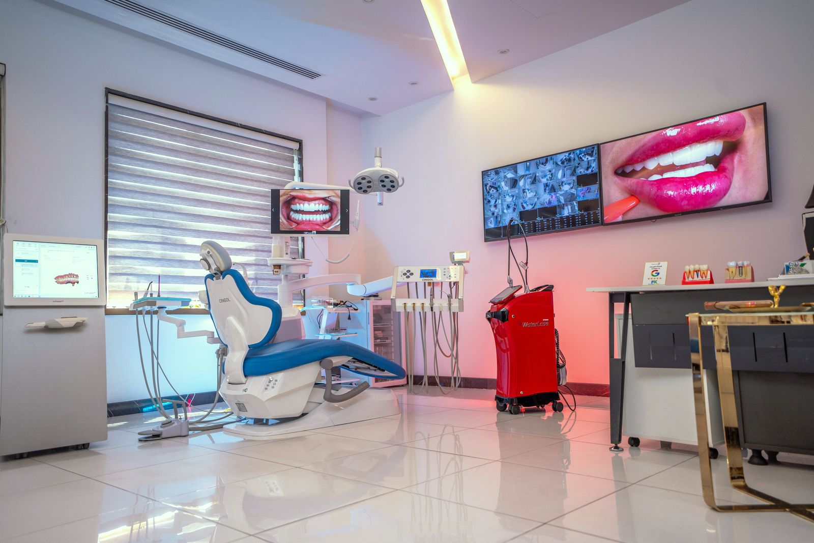 A treatment room with a red dental laser unit and wall screens