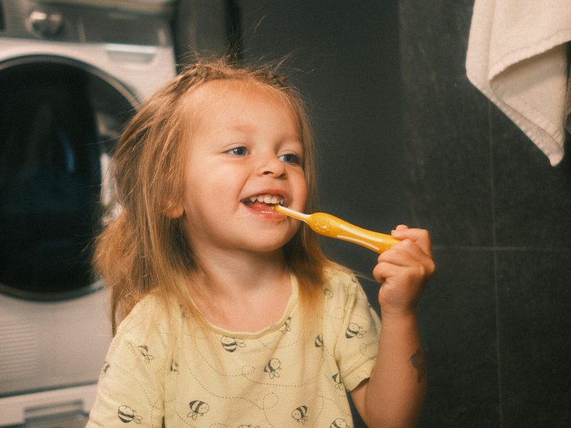 A smiling toddler brushing her teeth