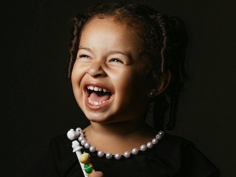 A laughing young girl holding a toothbrush